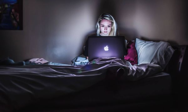 Mujer preocupada por el criptoinvierno mientras usa su laptop en la cama.
